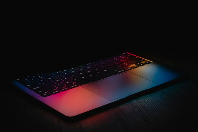 a light - up laptop has a dark background and blue keyboard