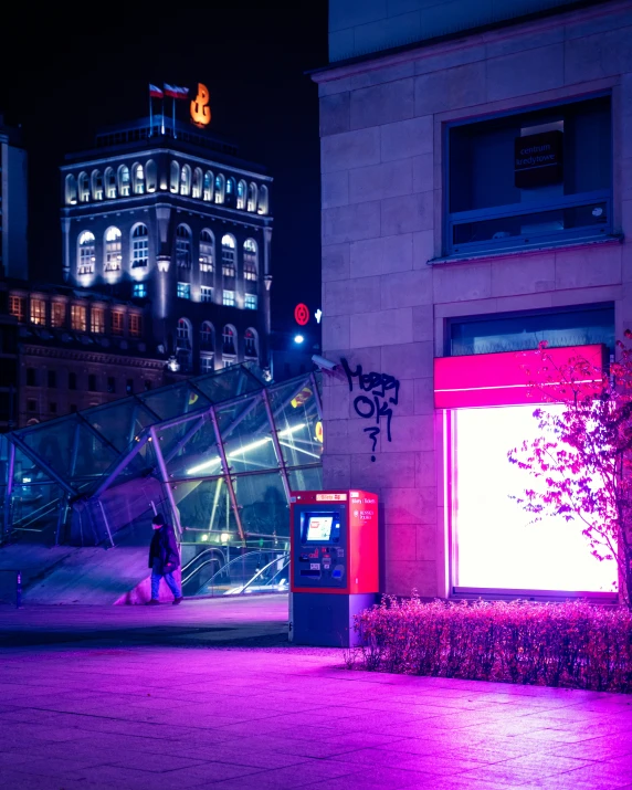 a woman is walking towards a large building that is lit up