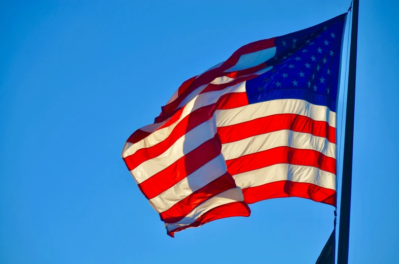 two american flags are waving in the wind