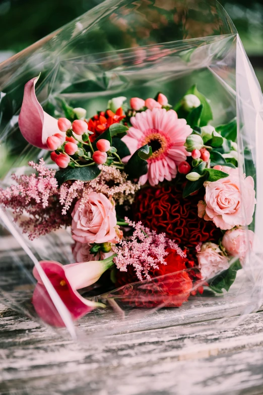 a bouquet of pink flowers sits on a piece of wood