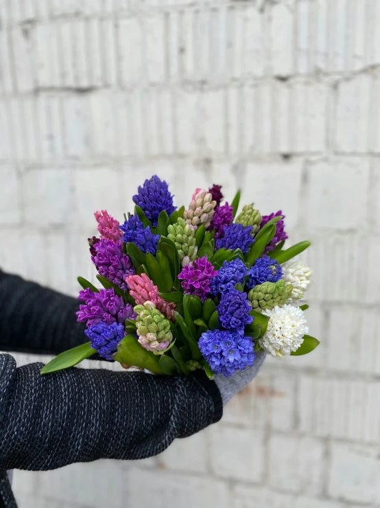 a bouquet of flowers are held up against a wall