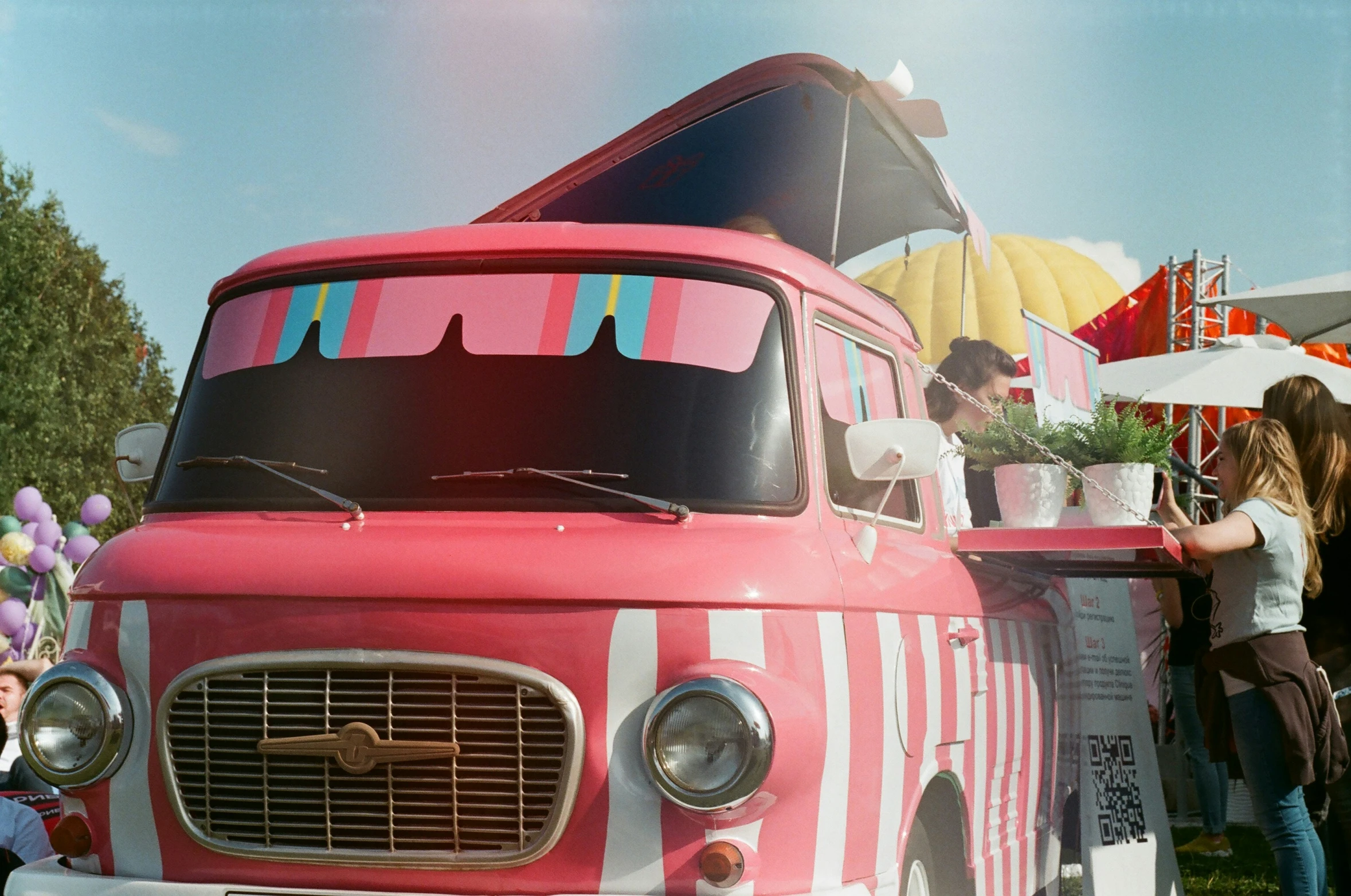 a pink van parked next to a group of people