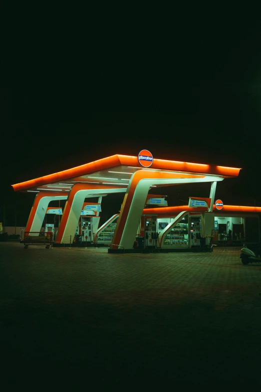 the gas station is lit up and has orange lights