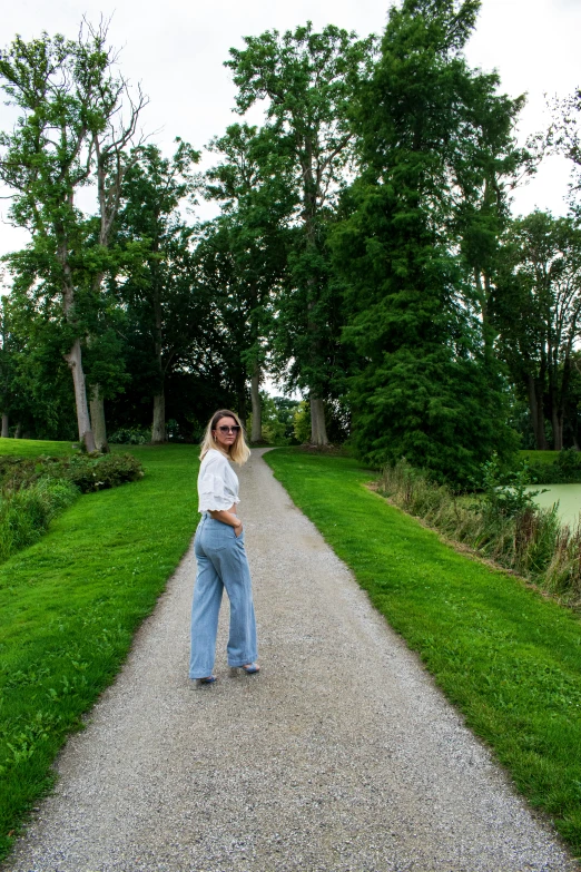 a woman is standing on a path in a park