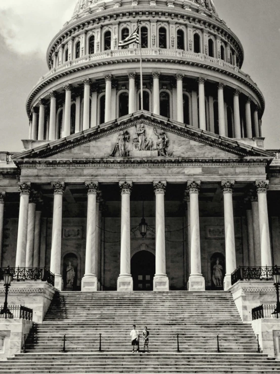 a large building with columns on both sides of the building and people climbing stairs