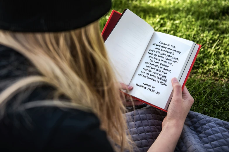 the woman is reading a book on the grass