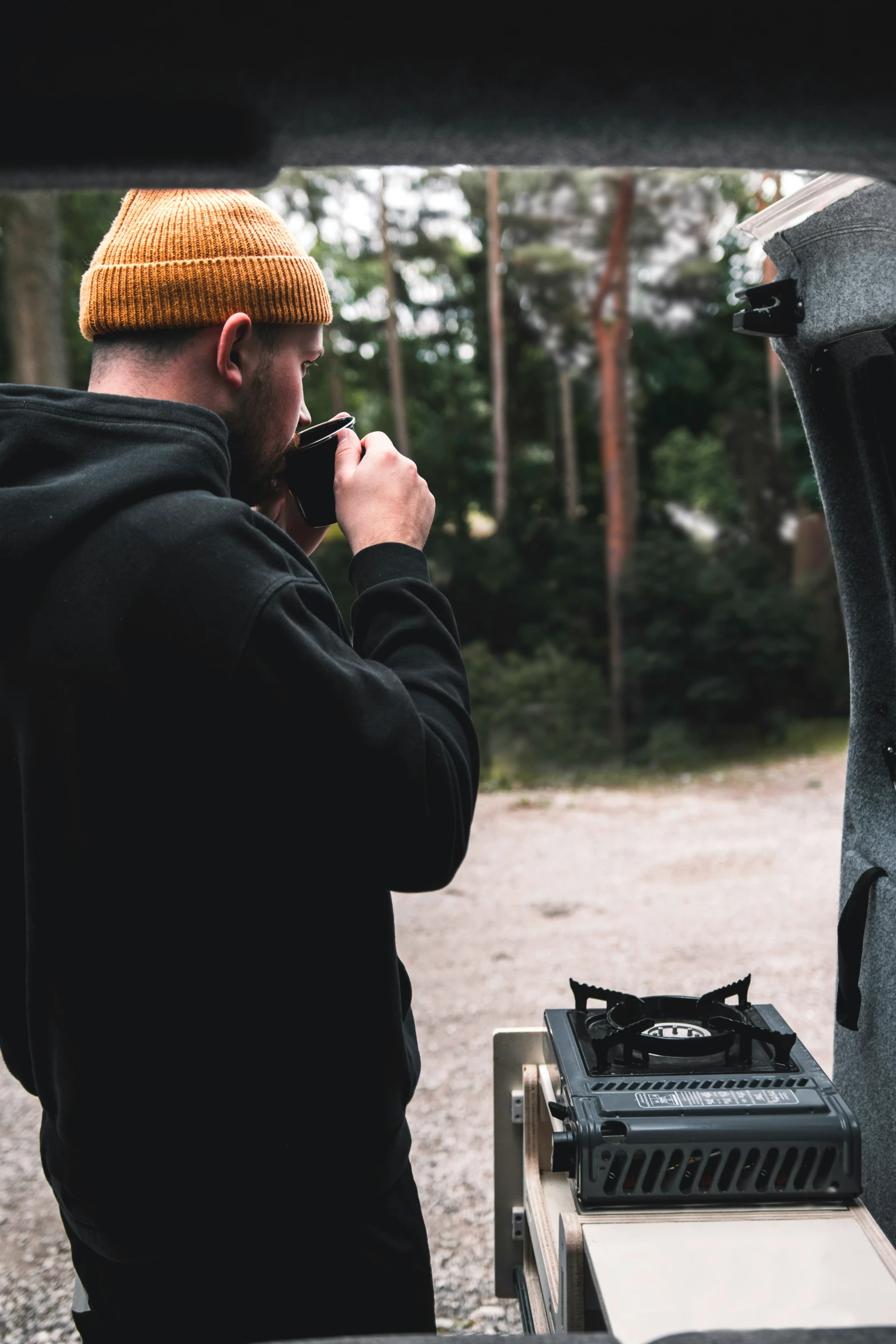 a man in a beanie taking a picture with his cell phone