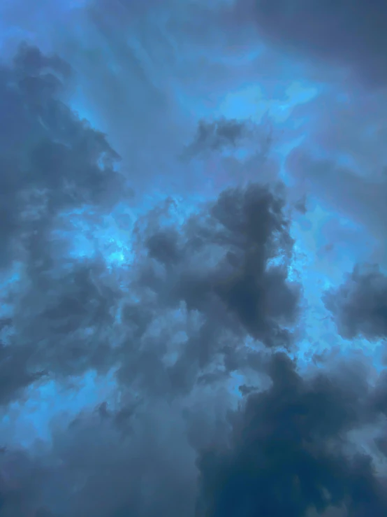 a plane flying through the cloudy blue sky