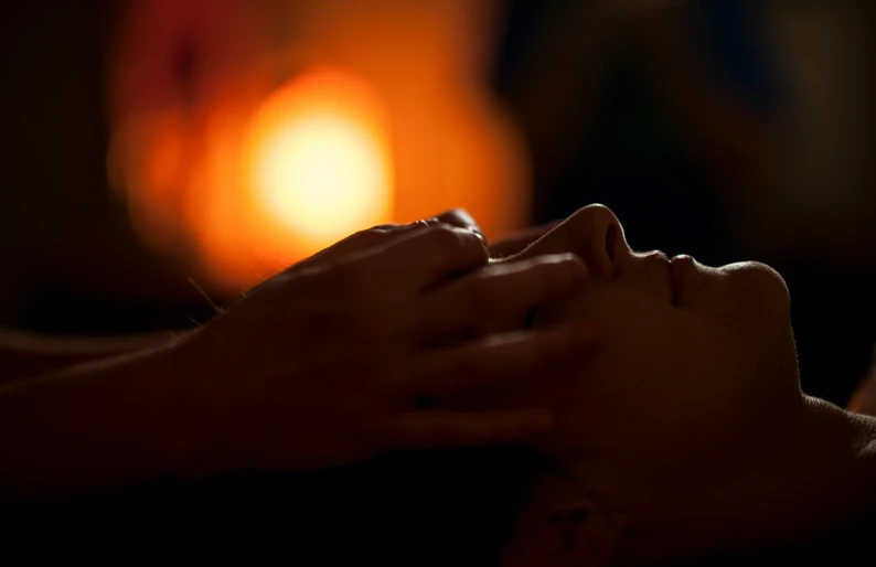 a woman having a massage with candles behind her