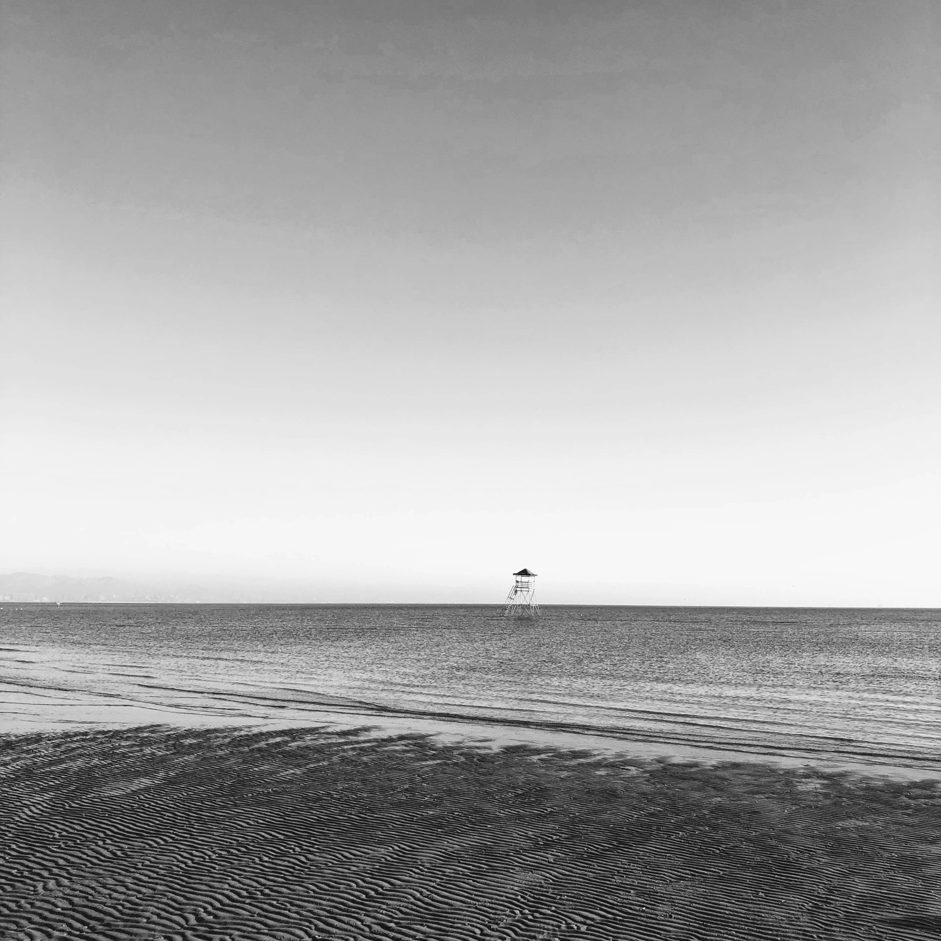 a small white light house in the middle of an ocean