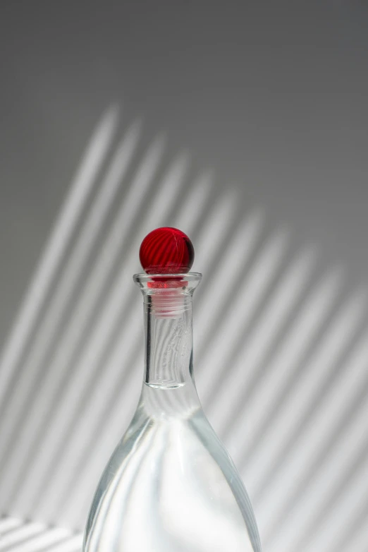 a glass bottle with red cap sitting on top of a table