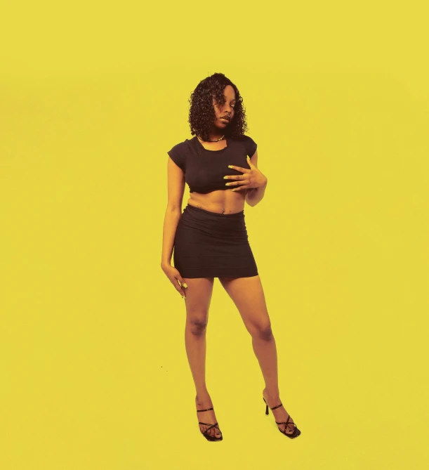 a woman posing in black clothes on yellow background