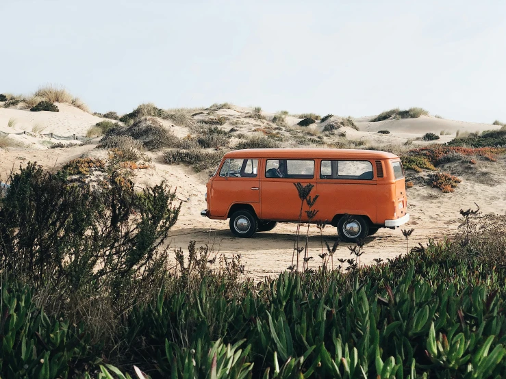 an old orange bus is parked on the side of a hill