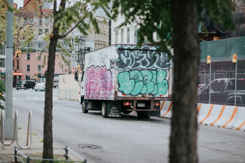 a box truck with graffiti on it going down a street