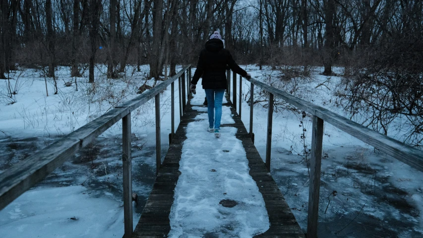 a person walking across a bridge in the snow