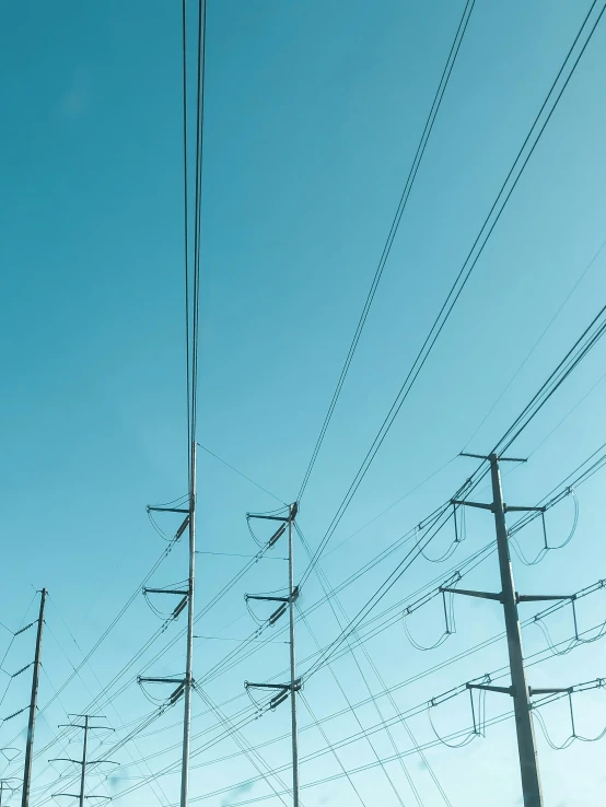 many electric wires and power lines with a blue sky behind