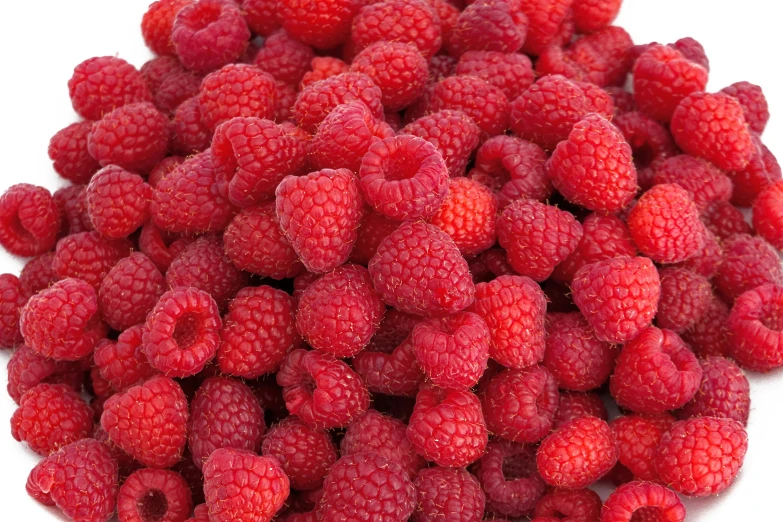 a pile of raspberries are shown on white