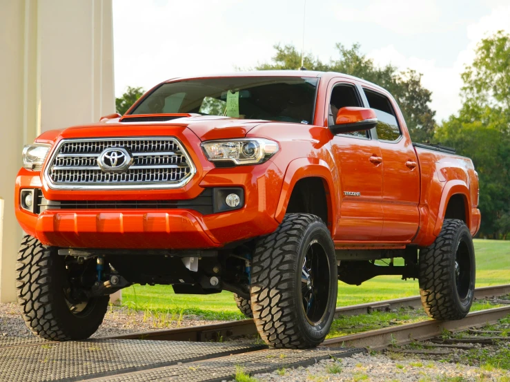 an orange toyota pickup is parked on the railroad