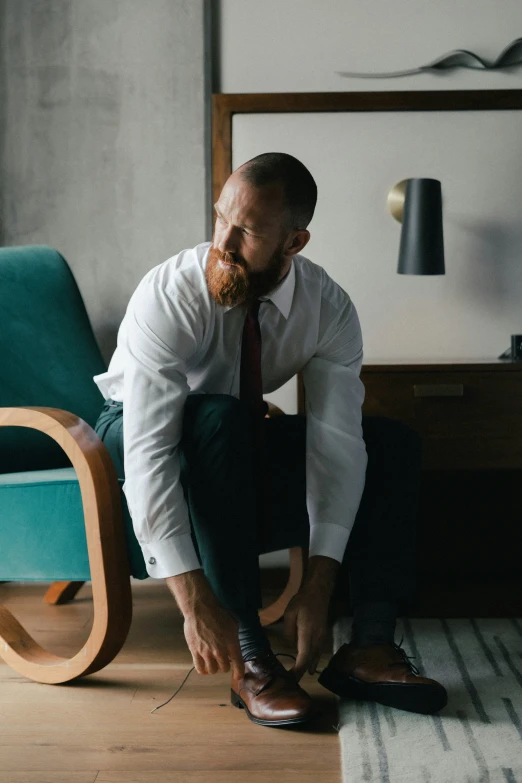 a man in a shirt and tie tying his shoes