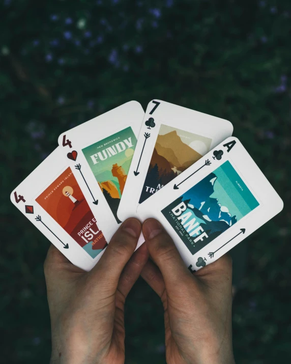 a person holding four playing cards with their hands