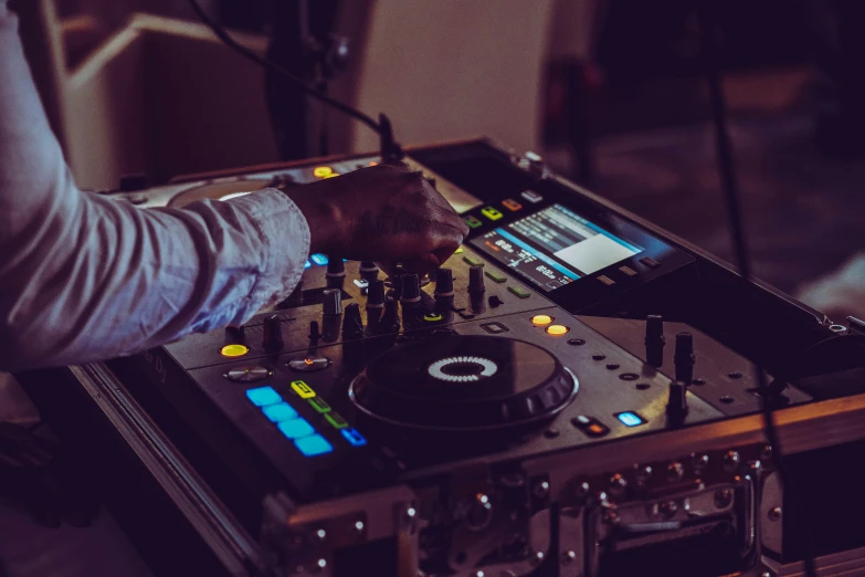 the dj at the turntable controls his electronic equipment