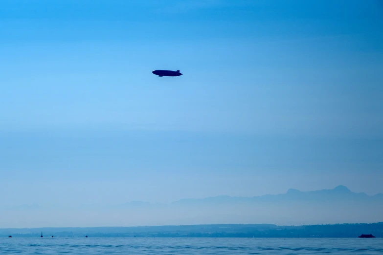 two boats sailing in the ocean and one plane is flying overhead