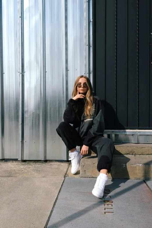 the woman is sitting on the cement steps wearing white sneakers