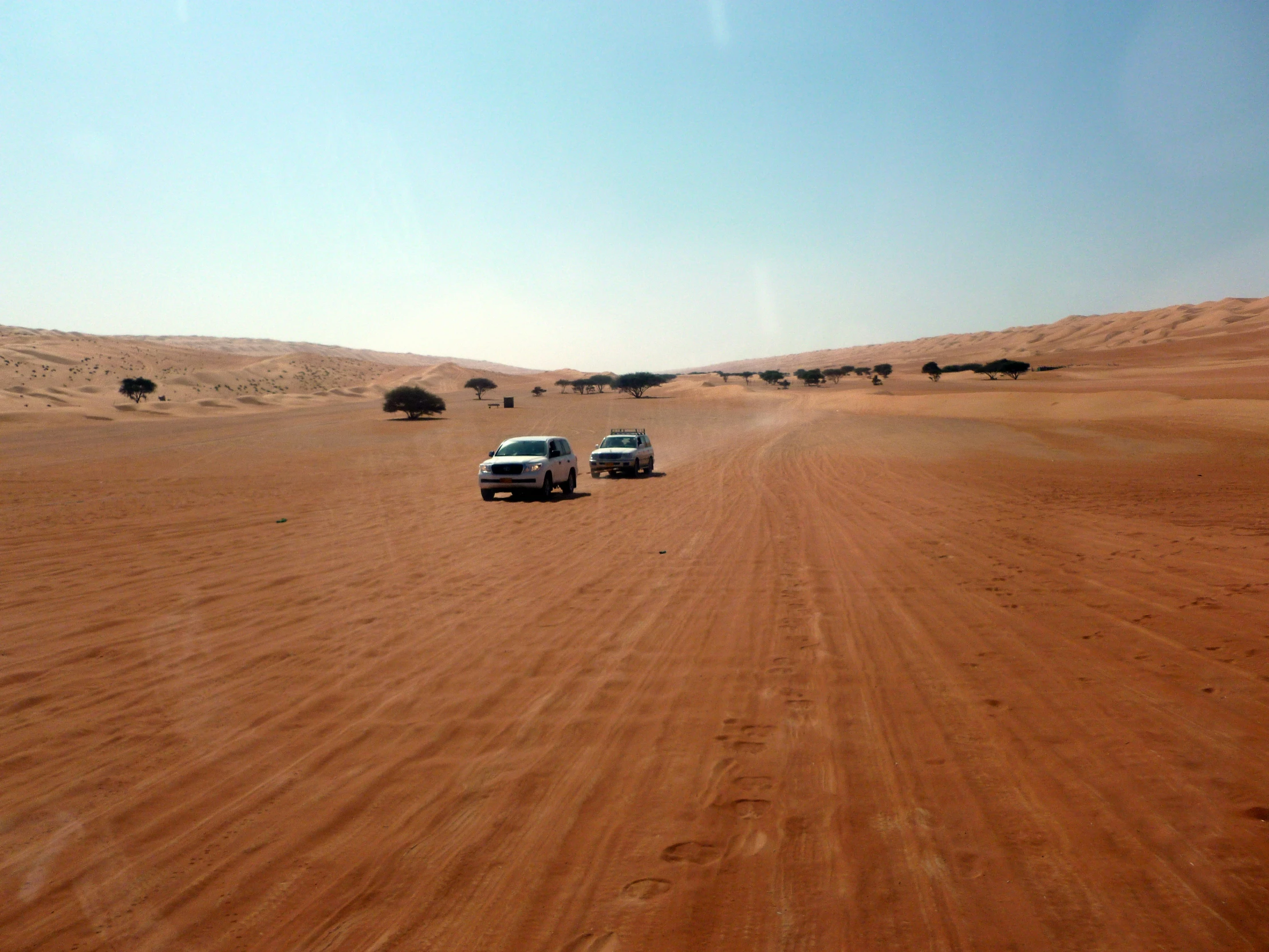 two vehicles driving through the sand in the desert