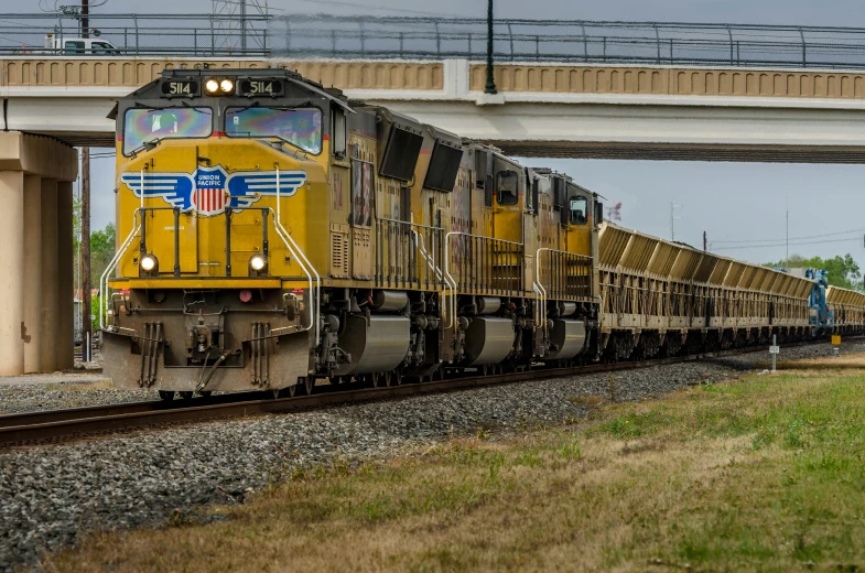 a train traveling down the tracks under a bridge