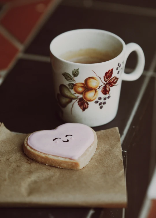 a small heart shaped cookie next to a cup of coffee