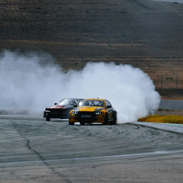 two cars driving on a race track with smoke trailing from the back