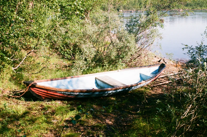 a boat on the shore next to a body of water