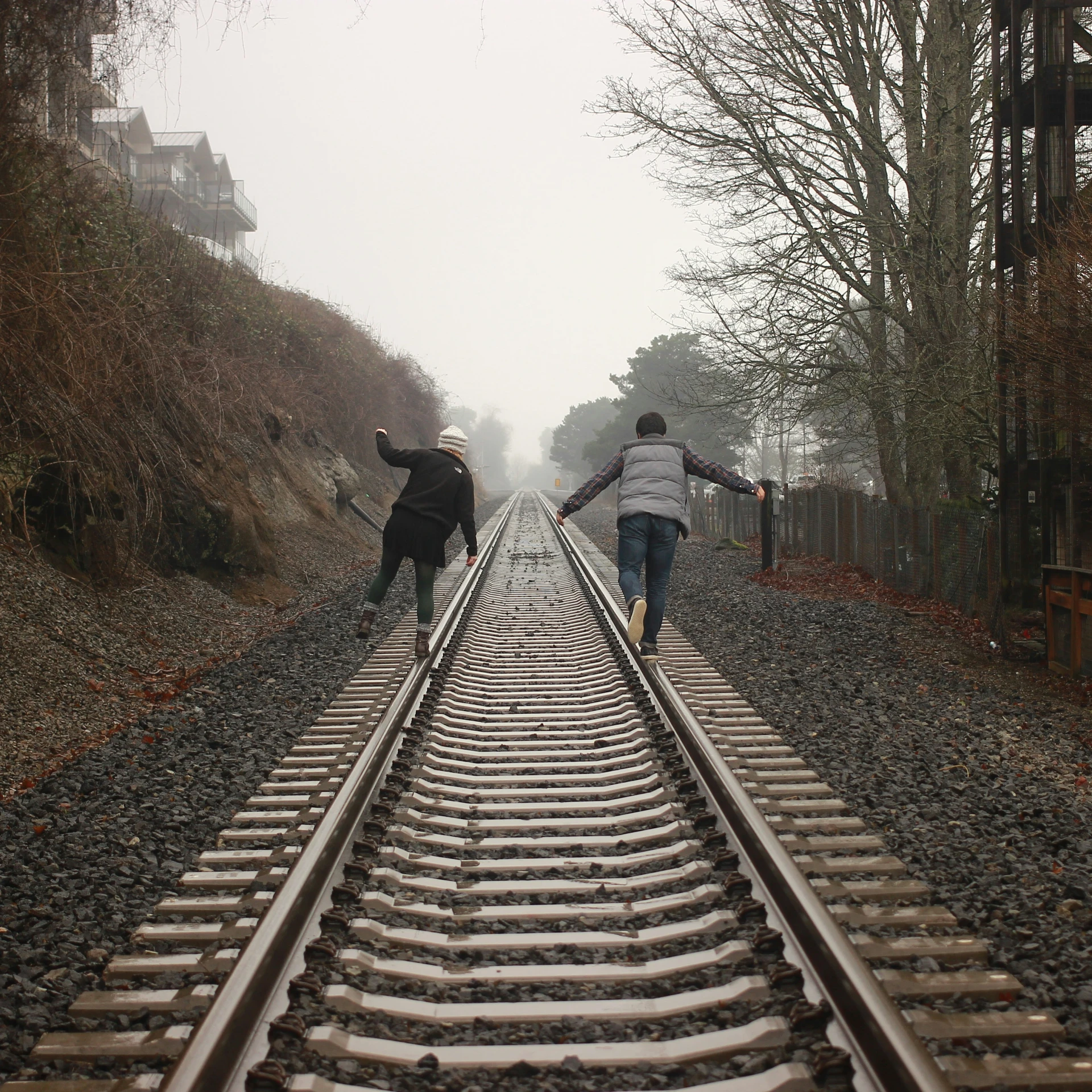 three people running down the railroad tracks in the rain