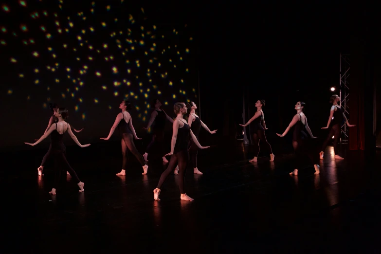 dancers are shown on stage in a dark room