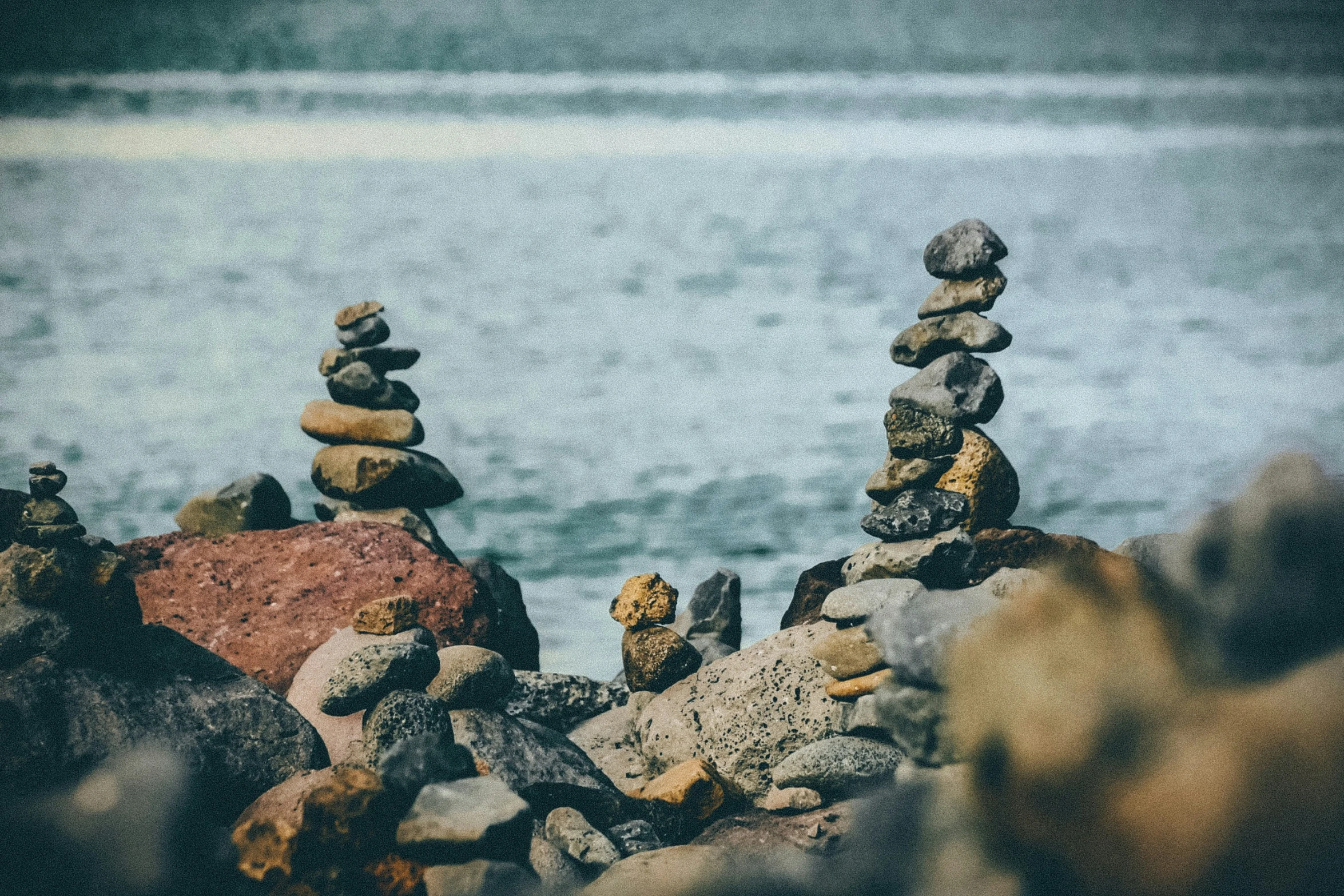 rocks piled up next to the water on top of each other