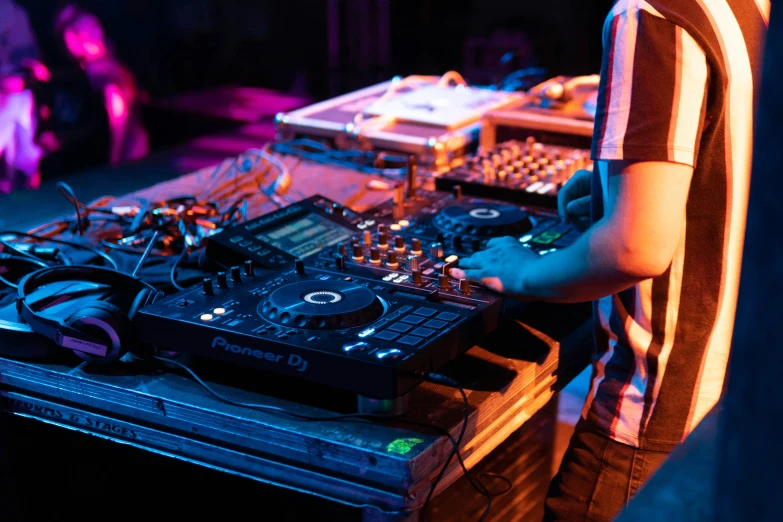 a man standing next to a dj's console with electronics around him