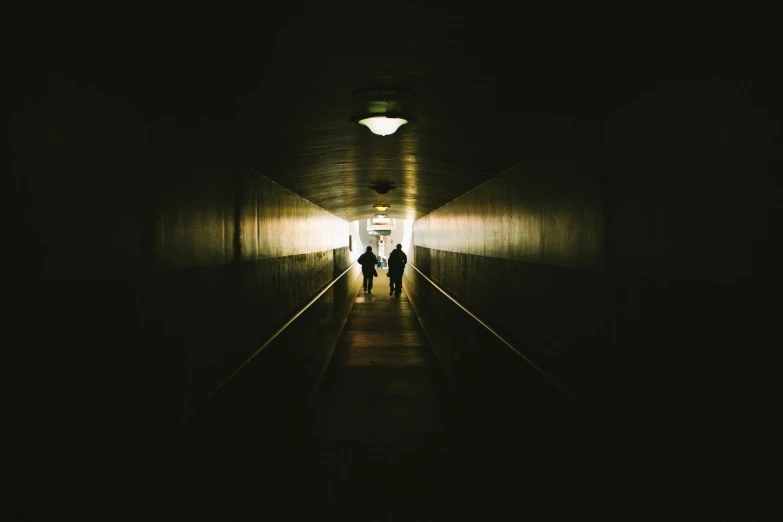 two people walking down a dark, empty hallway