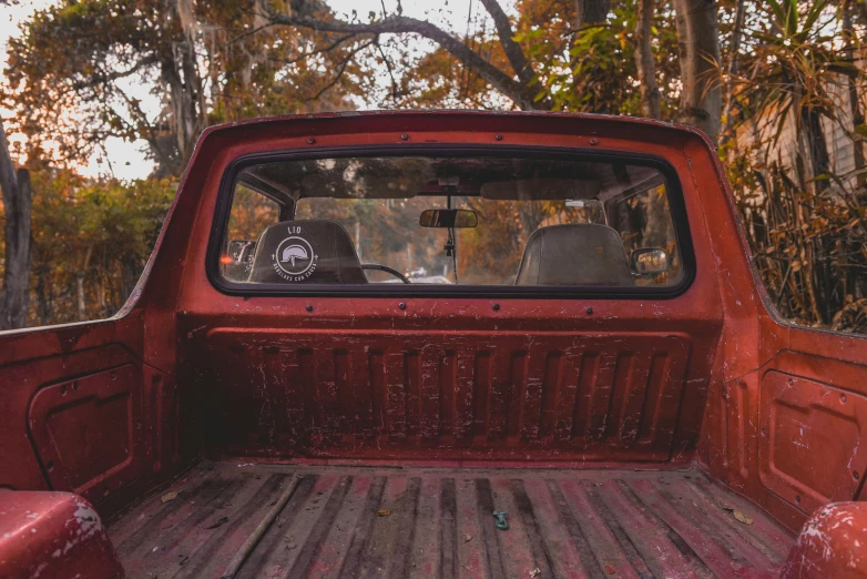 an old red truck has been parked in the woods