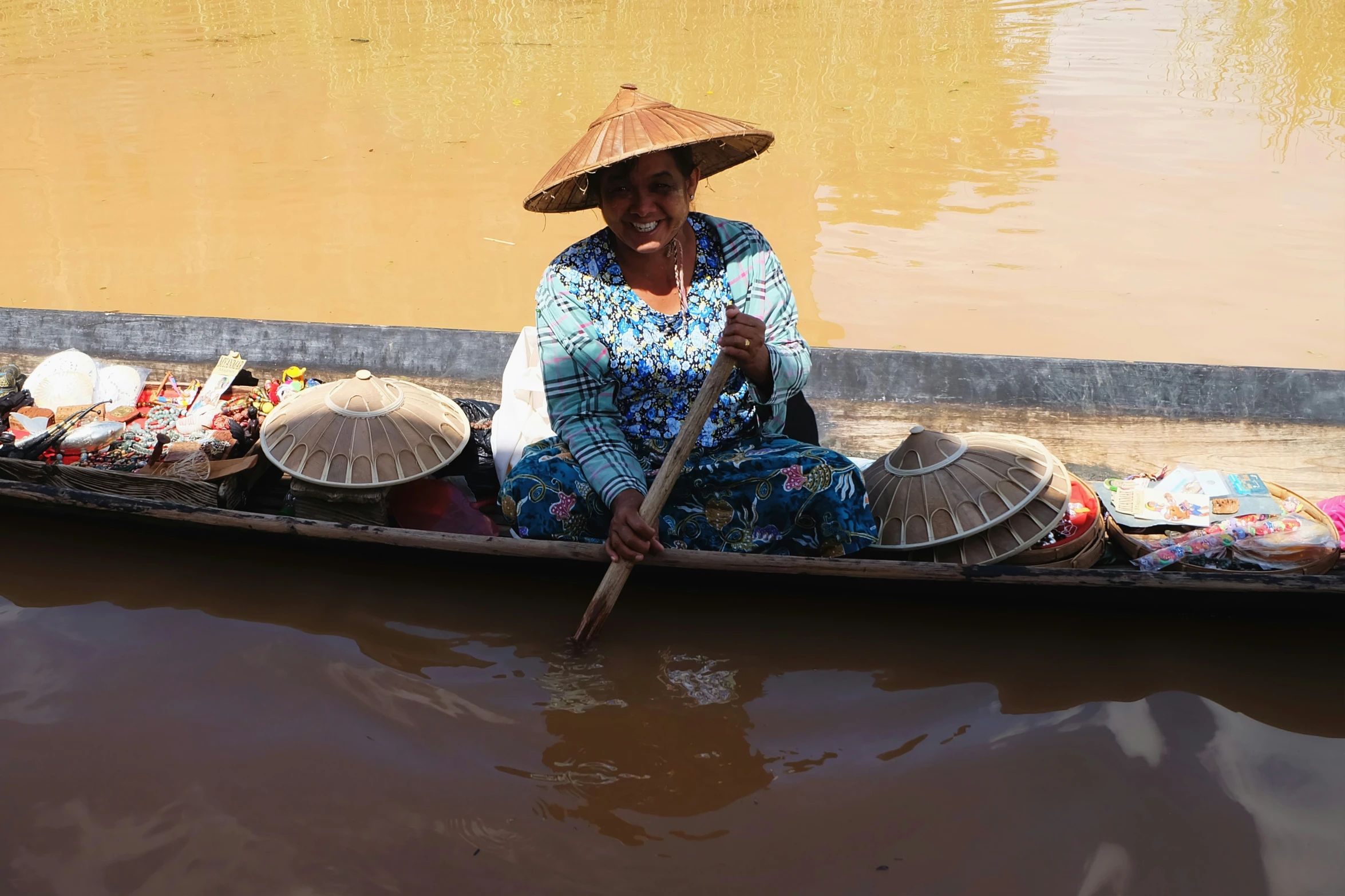 a woman on a boat has hats and a stick in her hand