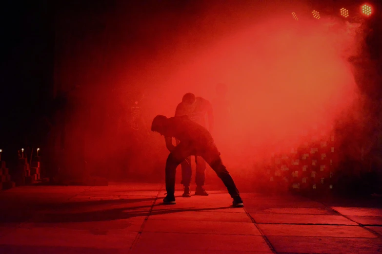 people in silhouette at night by bright red colored spray