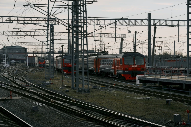 two trains passing each other on tracks under wires