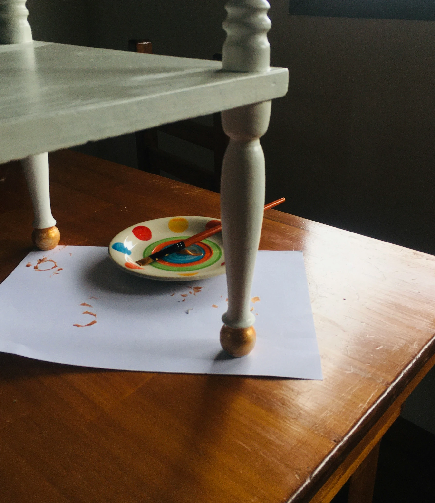 an image of a colorful plate and spoon on a paper on the edge of a table