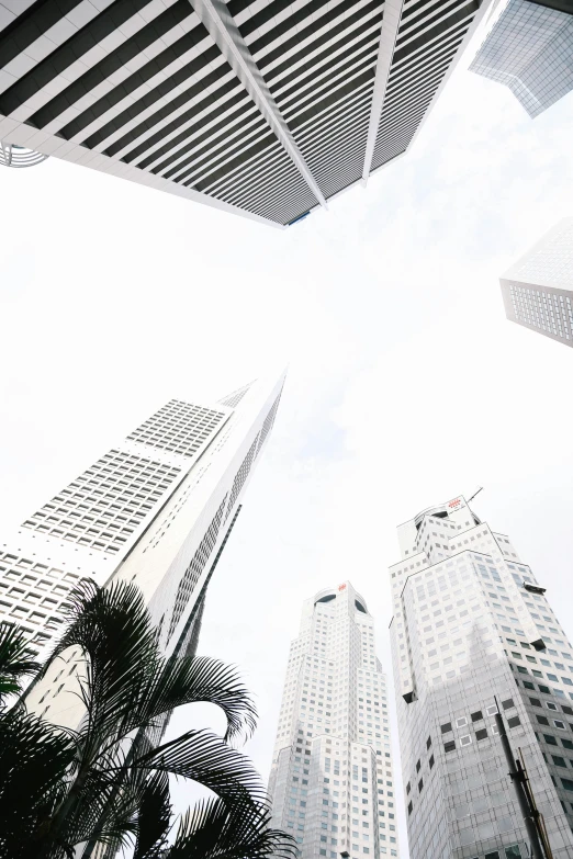 a pograph of a tall building taken from below looking up at other buildings