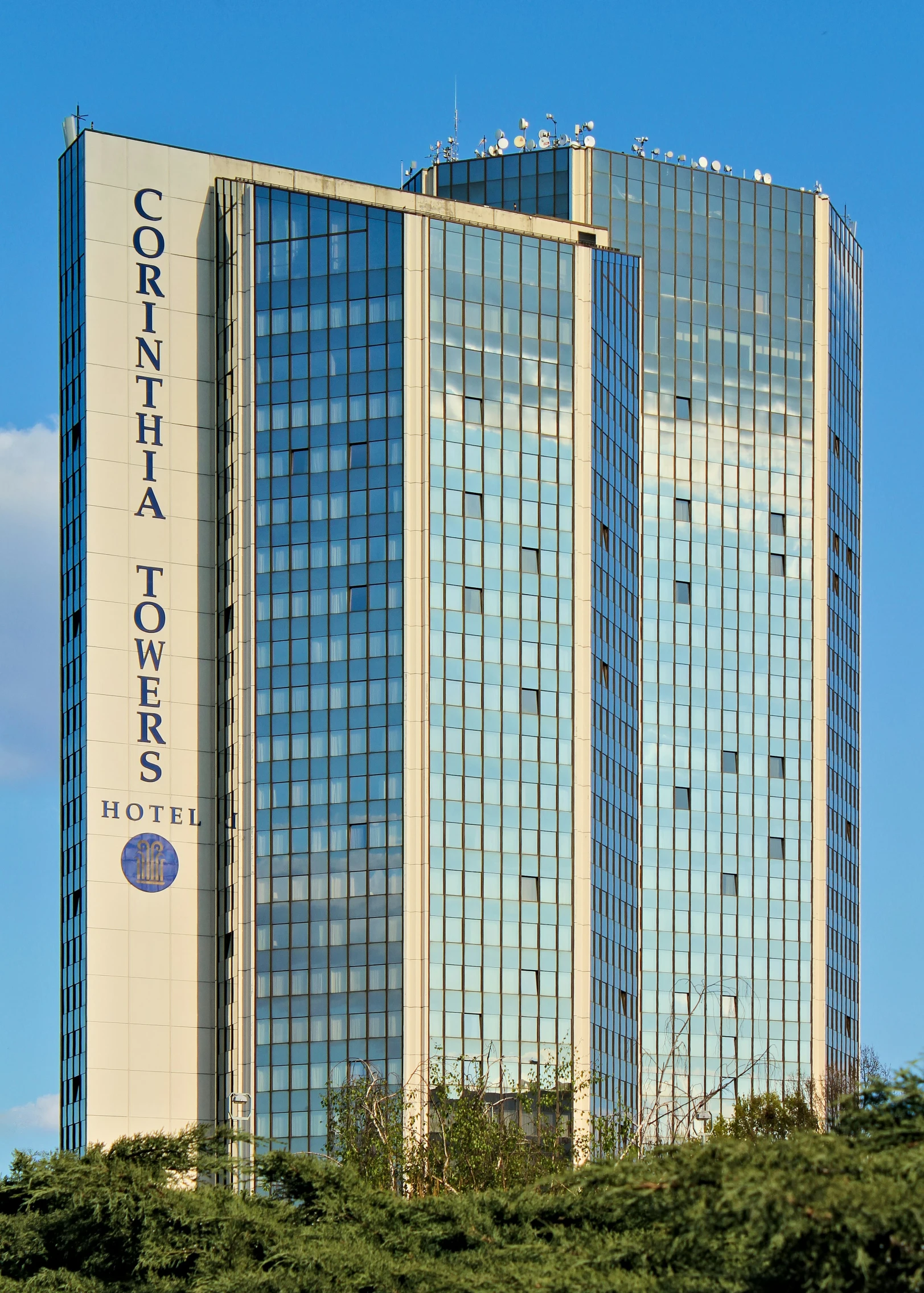 a tall building with a sky background and trees on top