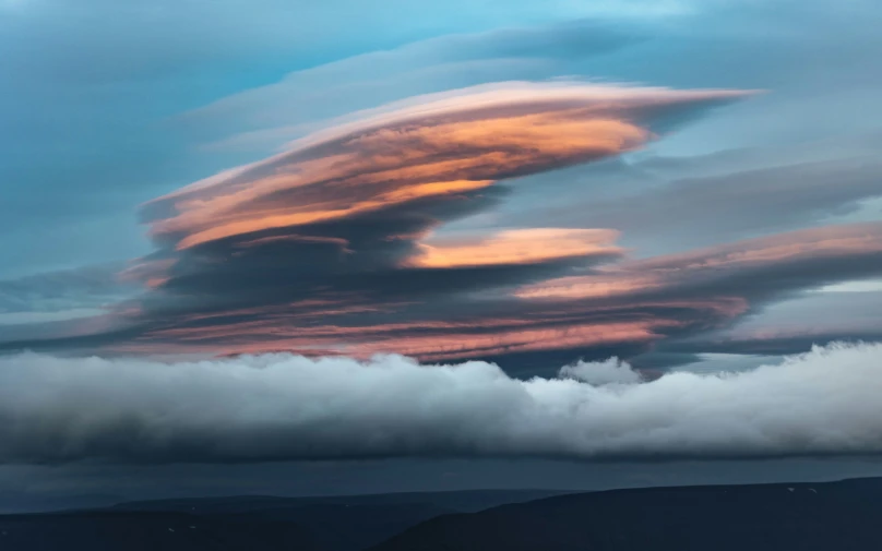colorful clouds loom over a hilly area in the distance