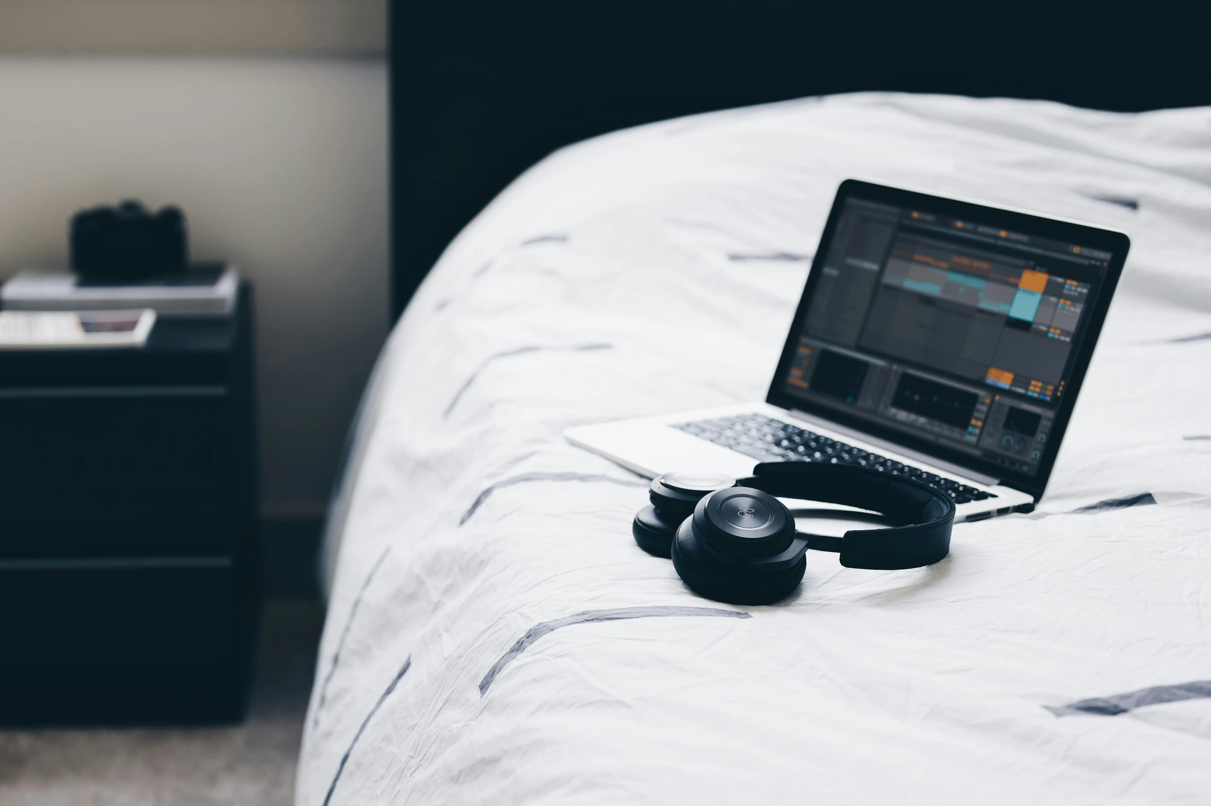 an open laptop is on a bed with headphones on top