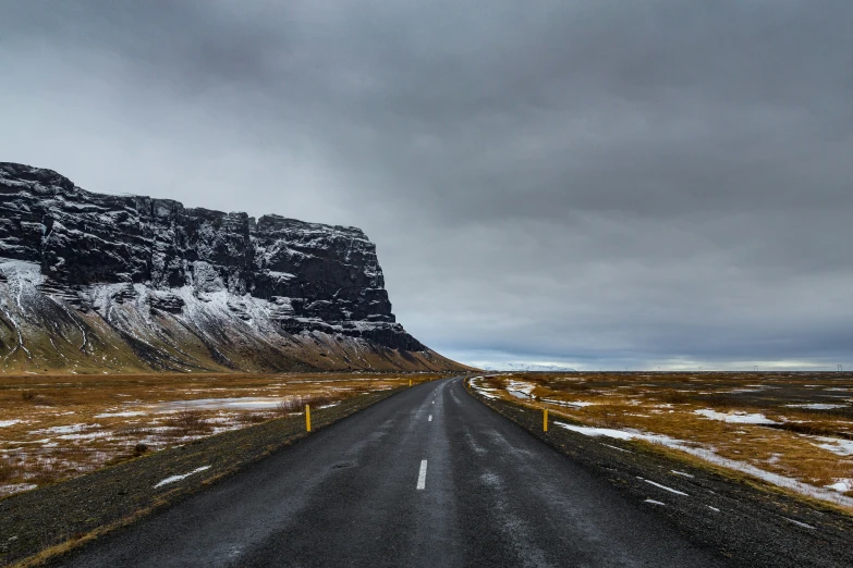 an empty road in front of the mountains