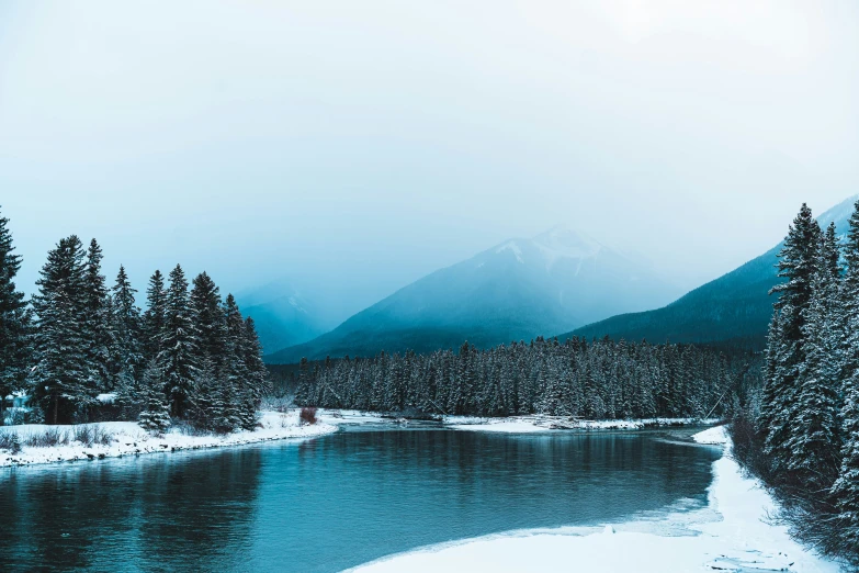 a lake surrounded by snow covered evergreen trees