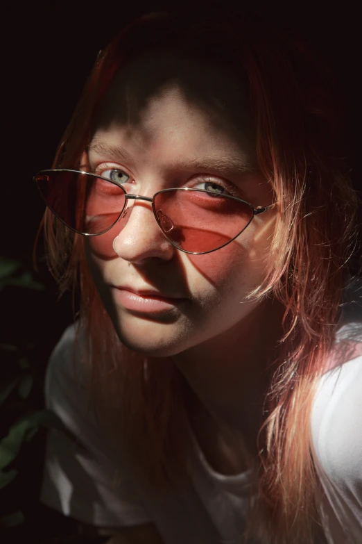 a girl with pink glasses is looking at the camera