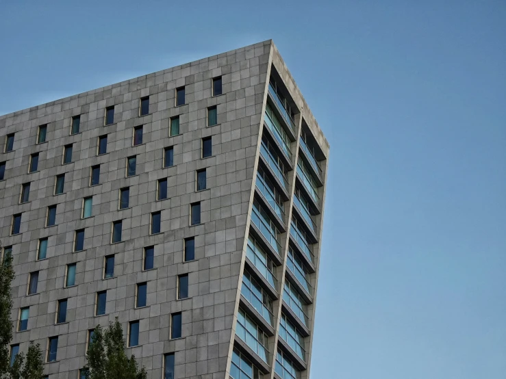 a very tall grey building with windows and a clock at the top